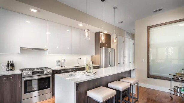 A modern kitchen with a central island, stainless steel appliances, and pendant lighting.