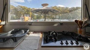 A kitchen with gas stoves, a window overlooking a parking area with a covered structure, and a view of trees. - L'Escapade - RAMONVILLE SAINT AGNE (RAMONVILLE SAINT AGNE)