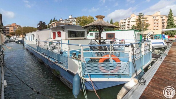 A narrow canal with a boat docked at the pier, surrounded by buildings and trees. - L'Escapade - RAMONVILLE SAINT AGNE (RAMONVILLE SAINT AGNE)