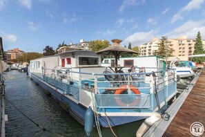 A narrow canal with a boat docked at the pier, surrounded by buildings and trees. - L'Escapade - RAMONVILLE SAINT AGNE (RAMONVILLE SAINT AGNE)