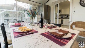 Un comedor moderno con una mesa de mármol, ventanas de vidrio transparente y una cocina al fondo.