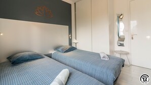 Habitación de hotel con dos camas, un espejo grande y una lámpara fijada a la pared.