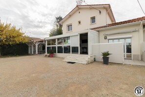 Une maison à deux étages dotée d’un patio couvert, d’un garage et d’une allée en gravier.