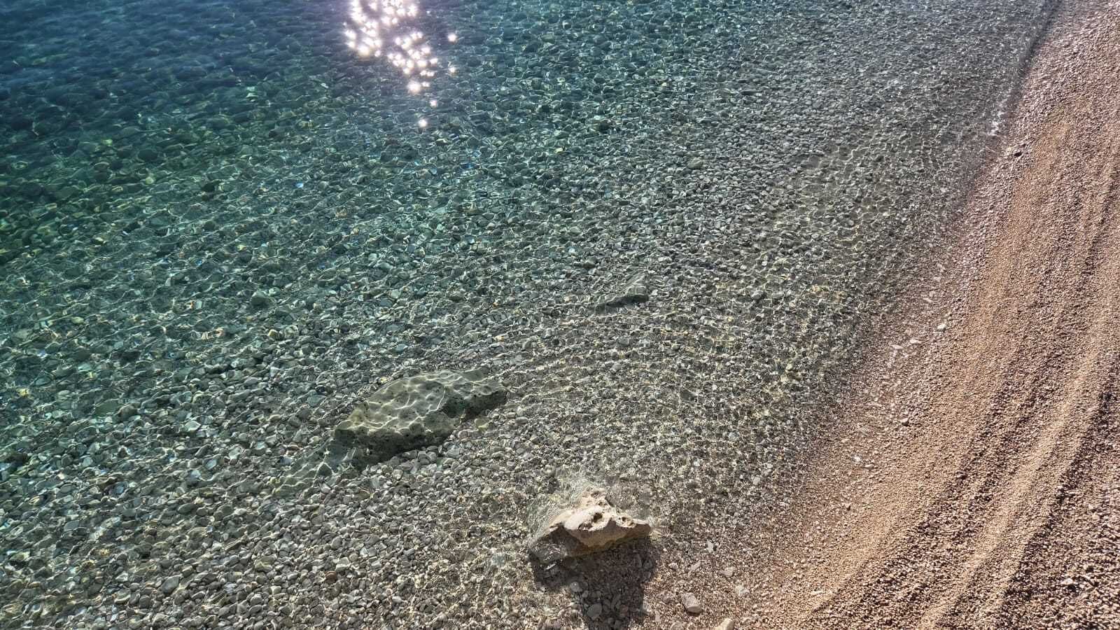 Una spiaggia con acque cristalline poco profonde e una costa sabbiosa.