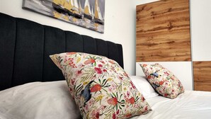 A bed with a black headboard, floral pillows, and a painting of sailboats on the wall. - Apartment Azure Suite in Lokva Rogoznica (Lokva Rogoznica)