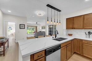 Eine moderne Küche mit weißen Arbeitsplatten, Holzschränken und Pendelleuchten.