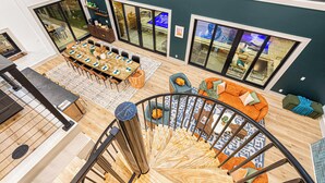 Un vaste espace de vie comprenant une table à manger, des canapés et un escalier en colimaçon.