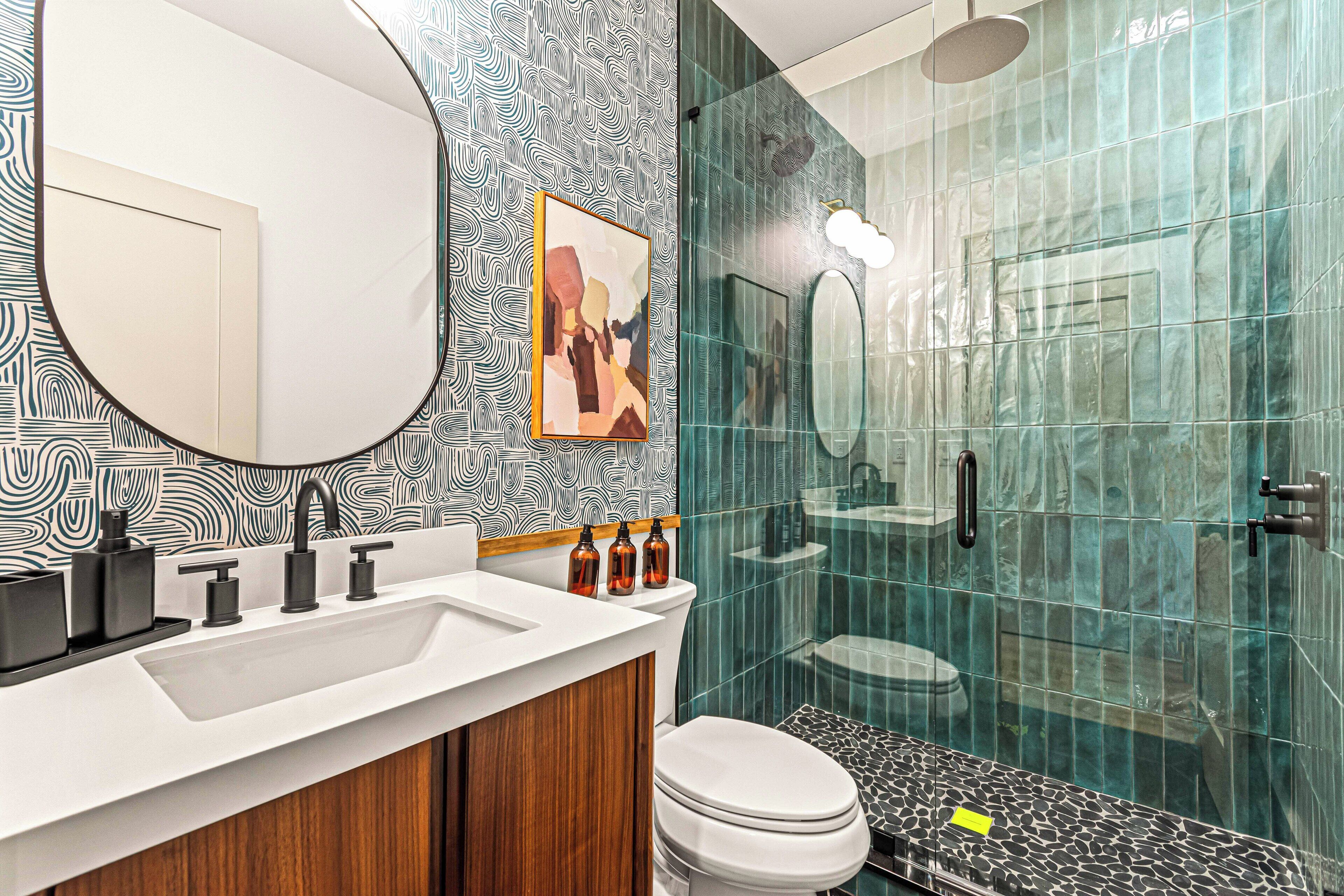 Une salle de bain moderne avec un lavabo blanc, un grand miroir et une douche à parois de verre.