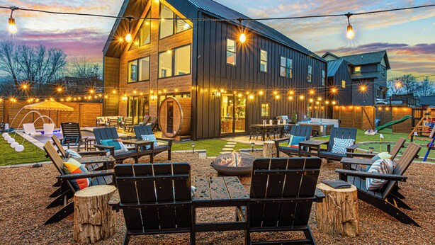 Une maison moderne dotée d’une terrasse, d’un espace salon extérieur et de guirlandes lumineuses.