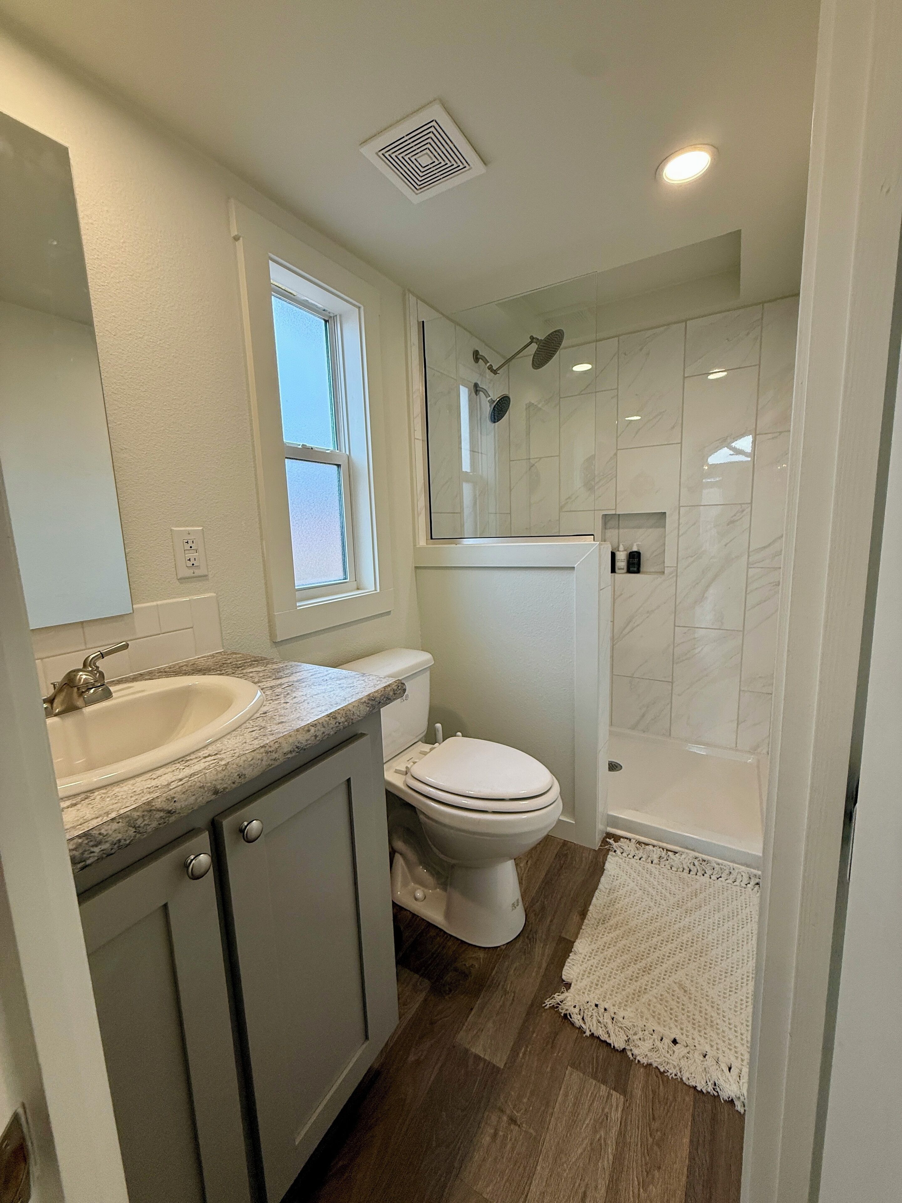 A modern bathroom with a sink, toilet, and walk-in shower.