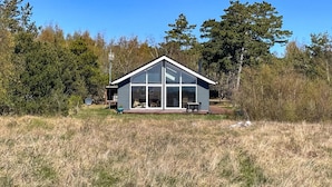 Una casa moderna con grandes ventanales, un patio con mobiliario exterior y una antena parabólica.