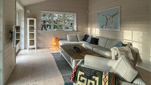 A cozy room with a striped sofa, a wooden coffee table, and a window with a view of trees. - Stunning home in Højby with WiFi (Højby)