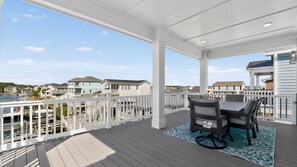 Una terraza techada al aire libre con una mesa y sillas, con vista a una zona residencial.