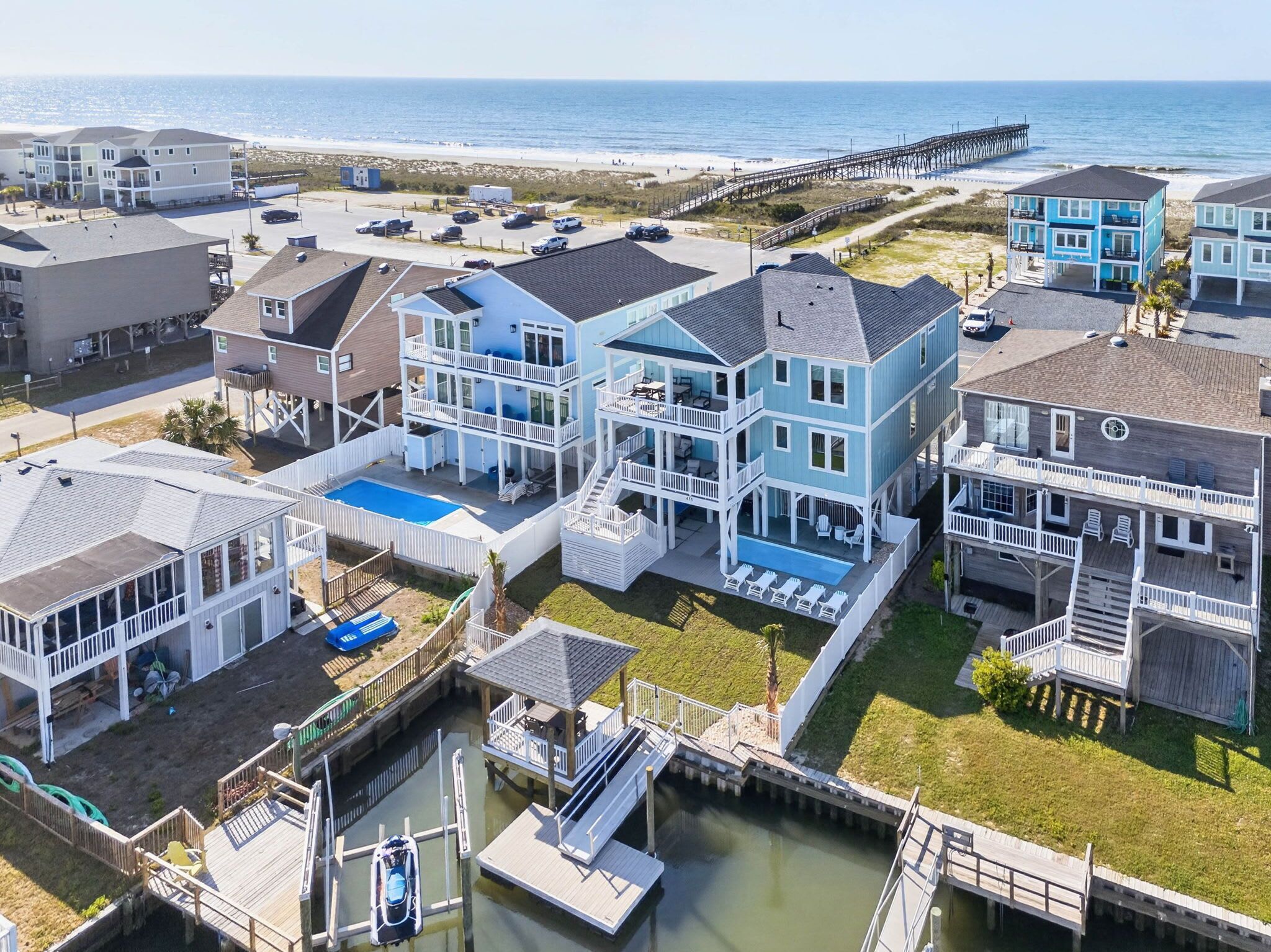 A coastal residential area with houses, a pier, and a beach.