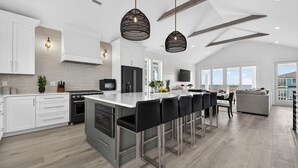 Une cuisine moderne avec des meubles blancs, des appareils en acier inoxydable et un îlot central doté de tabourets de bar.