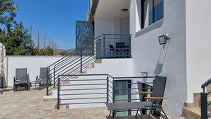 Ein modernes Gebäude mit einem Balkon, Sitzgelegenheiten im Freien und einer Treppe.