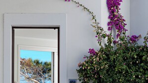 A white door with a view of a blue sky and a building with a balcony.