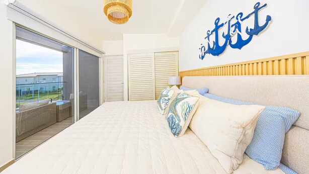 Een slaapkamer met een groot bed, uitzicht naar buiten en een decoratieve ankerhanger aan de muur.