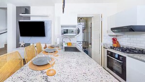 Eine moderne Küche mit Essbereich, Granit Arbeitsplatten, einem Flachbildfernseher und einem eingebauten Backofen.