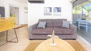 Ein modernes Wohnzimmer mit einem grauen Sofa, einem gewebten Sessel und einem Couchtisch aus Holz.