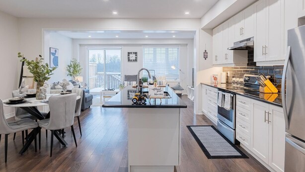 Une cuisine moderne avec des meubles blancs, un îlot central et un coin repas comprenant une table et des chaises.