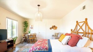 Ein Schlafzimmer mit einem Bett, einem Fernseher, einem Schreibtisch und einem Sessel.