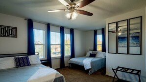Ein Schlafzimmer mit zwei Betten, einem Deckenventilator und einer Bank.