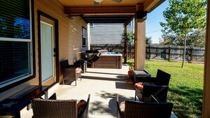 Eine überdachte Terrasse mit Korbmöbeln, einem Deckenventilator und einem Whirlpool.
