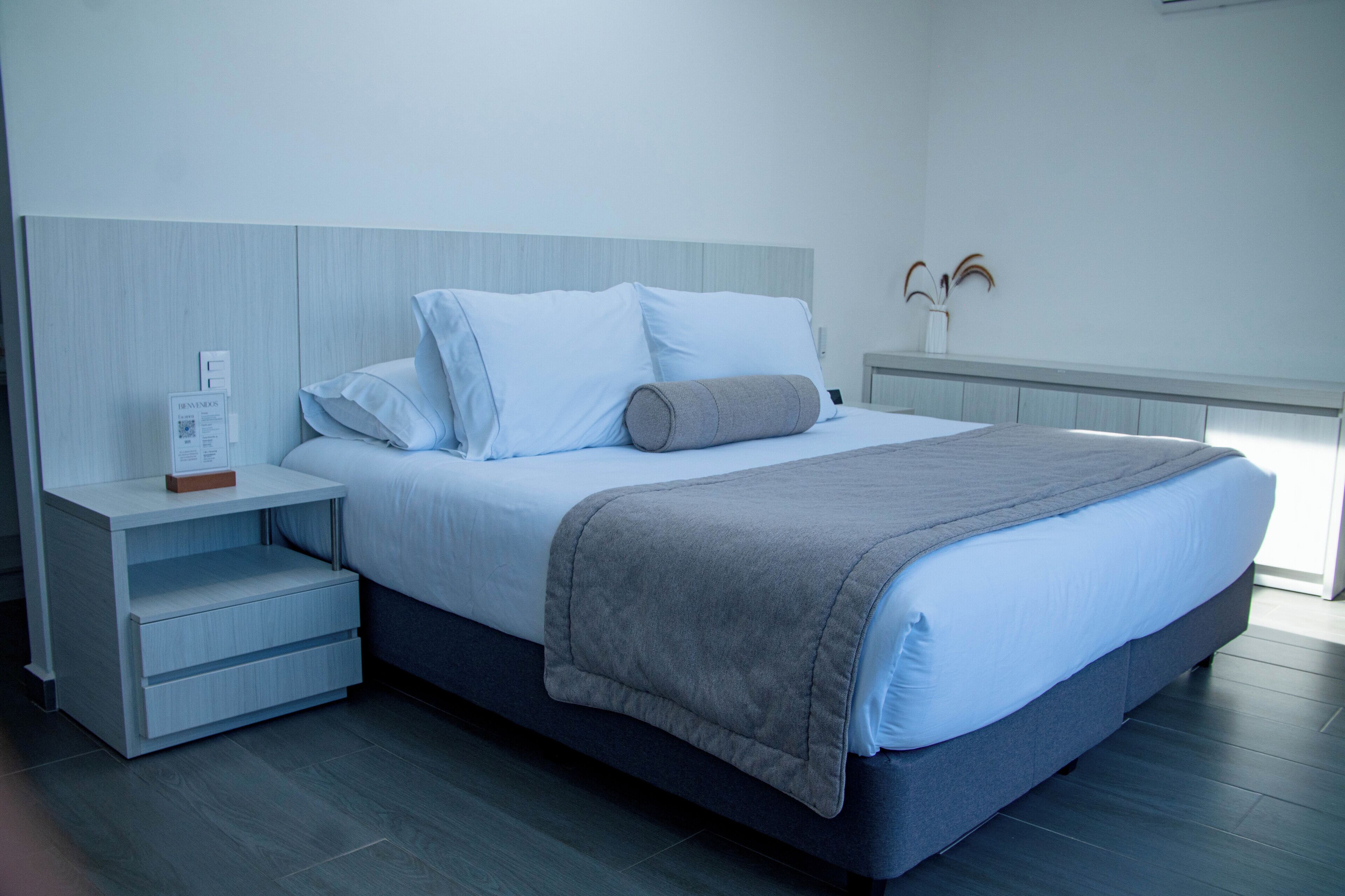 A modern bedroom with a bed, nightstand, and built-in shelving.