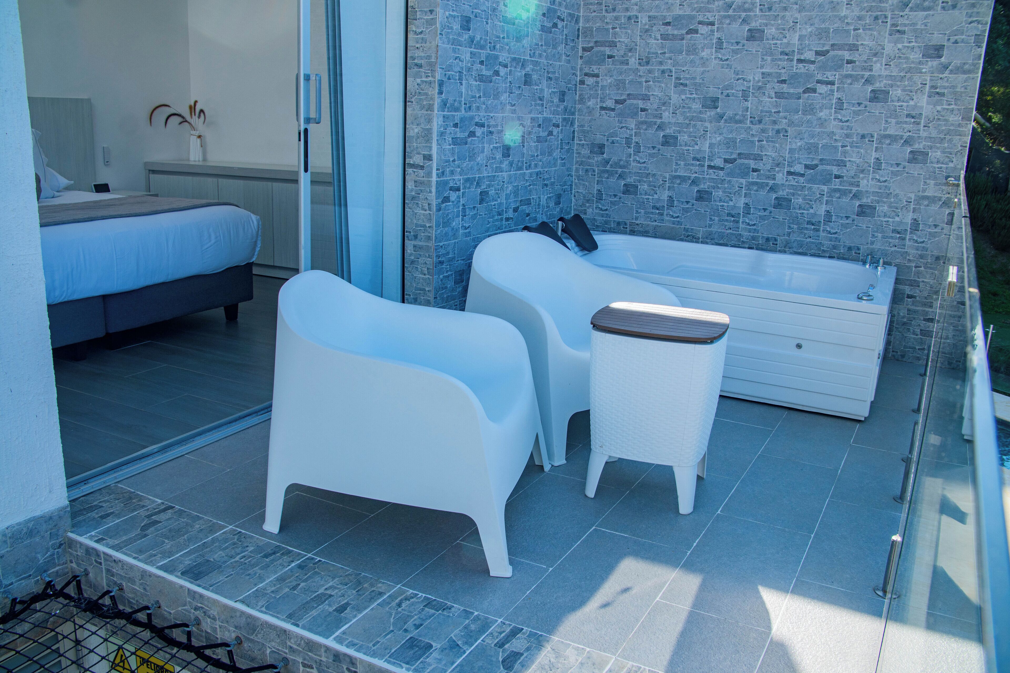 Ein modernes Schlafzimmer mit einem großen Bett, einer kleinen Sitzecke mit Tisch und einem separaten Badezimmer mit Badewanne.