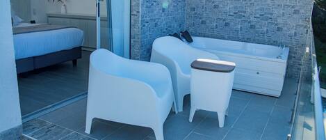 Ein modernes Schlafzimmer mit einem großen Bett, einer kleinen Sitzecke mit Tisch und einem separaten Badezimmer mit Badewanne.