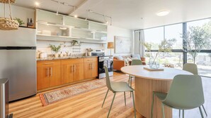 A modern kitchen with wooden cabinets, a built-in oven, and a dining area with a round table and chairs. - Hillcrest Hideaway – Stylish Loft in the Heart of SD (San Diego)