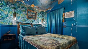 A room with a bed, a nightstand, a wall clock, and a power outlet.