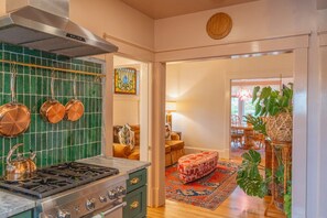 A kitchen with green tiles, copper pots, and a gas stove. - Luxe Historic West End • Walk to Downtown • Near Wake Forest • 2BDRM (Winston-Salem)