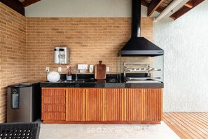 Eine kleine Küche mit Backsteinwand, schwarzem Dunstabzug, integriertem Backofen und Holz Arbeitsplatte.