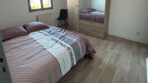 Ein Schlafzimmer mit Bett, Stuhl, Kleiderschrank und Fenster.