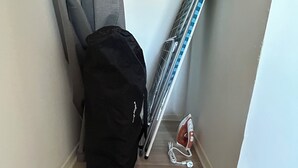 Eine Raumecke mit einer schwarzen Tasche, einer Paare Krücken und einem Bügeleisen auf dem Boden.