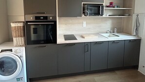 Eine kompakte Küche mit Waschmaschine, Mikrowelle und einer Pendelleuchte.