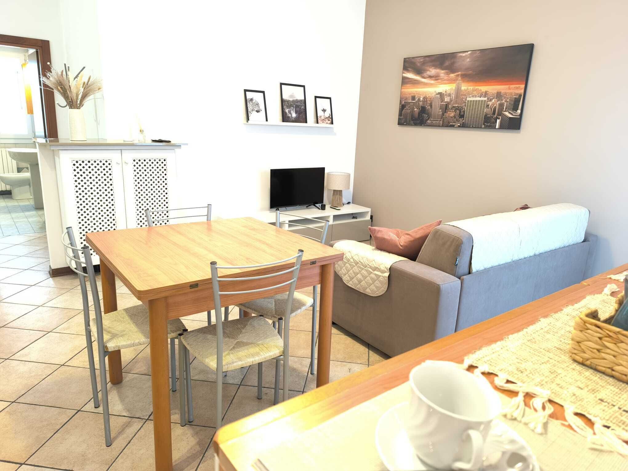Un salon moderne avec une table à manger en bois, deux chaises, un canapé et un téléviseur.