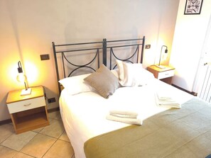 A neatly made bed with a metal headboard, two bedside tables with lamps, and a framed picture on the wall. - Città di Brescia adorable 4 person apartment with AC in Brescia Hospital Area (Brescia)