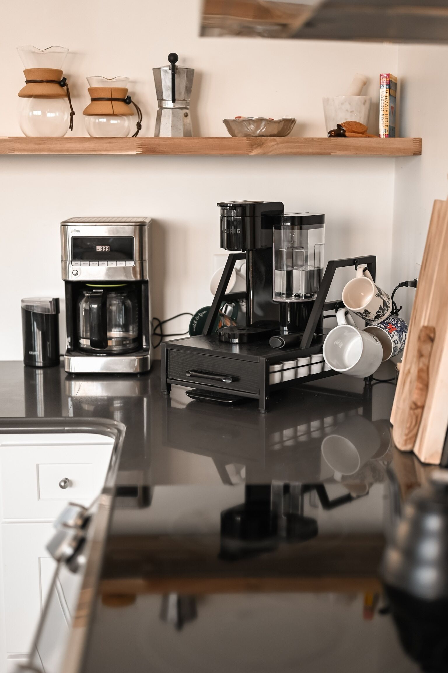 Une cuisine équipée d’une machine à café, d’une bouilloire et d’un moulin à café, le tout posé sur le plan de travail.