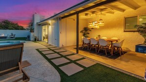 Uma casa moderna com varanda, área de refeições e piscina.