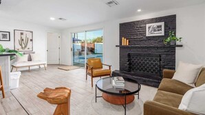 Uma sala de estar moderna com lareira, uma porta de vidro que dá para uma piscina e um sofá.