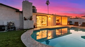 Uma casa moderna com piscina, um pátio e uma garagem.