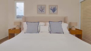 Camera da letto con un letto, due comodini, due lampade e due quadri appesi al muro.