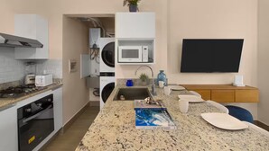 Una cucina moderna con un piano di lavoro in granito, elettrodomestici integrati, un forno a microonde e una TV a schermo piatto.