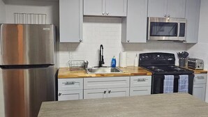 A modern kitchen with grey cabinets, a stainless steel refrigerator, a microwave, and a wooden countertop. - Spacious 4-bedroom house in New Orleans with AC (New Orleans)