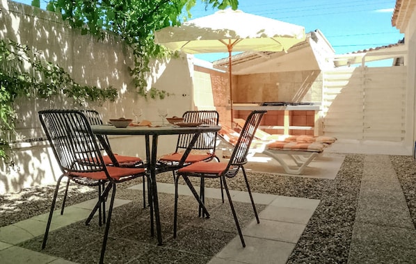 An outdoor patio with a round table and four chairs, a white umbrella, and a brick wall. - 1 bedroom beautiful home in Vaison-la-Romaine (Vaison-la-Romaine)