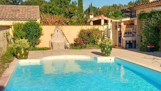 A swimming pool with a tiled deck, surrounded by greenery and a small building with a tiled roof. - Lovely home in Vaison-la-Romaine with house a panoramic view (Vaison-la-Romaine)