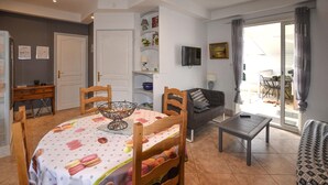 A dining area with a table set for four, a sofa, a TV, and a view of the outside. - Lovely home in Vaison-la-Romaine with house a panoramic view (Vaison-la-Romaine)